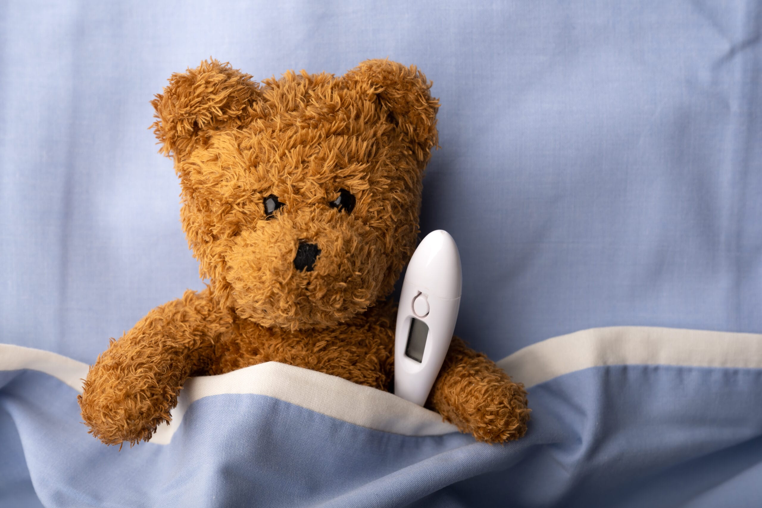 En kosebamse og termometer i lommen på uniformen til en sykepleier 